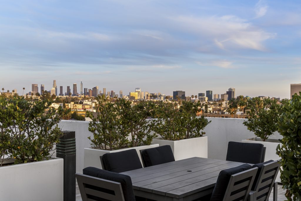 Rooftop terrace seating area overlooking downtown city skyline at sunset.