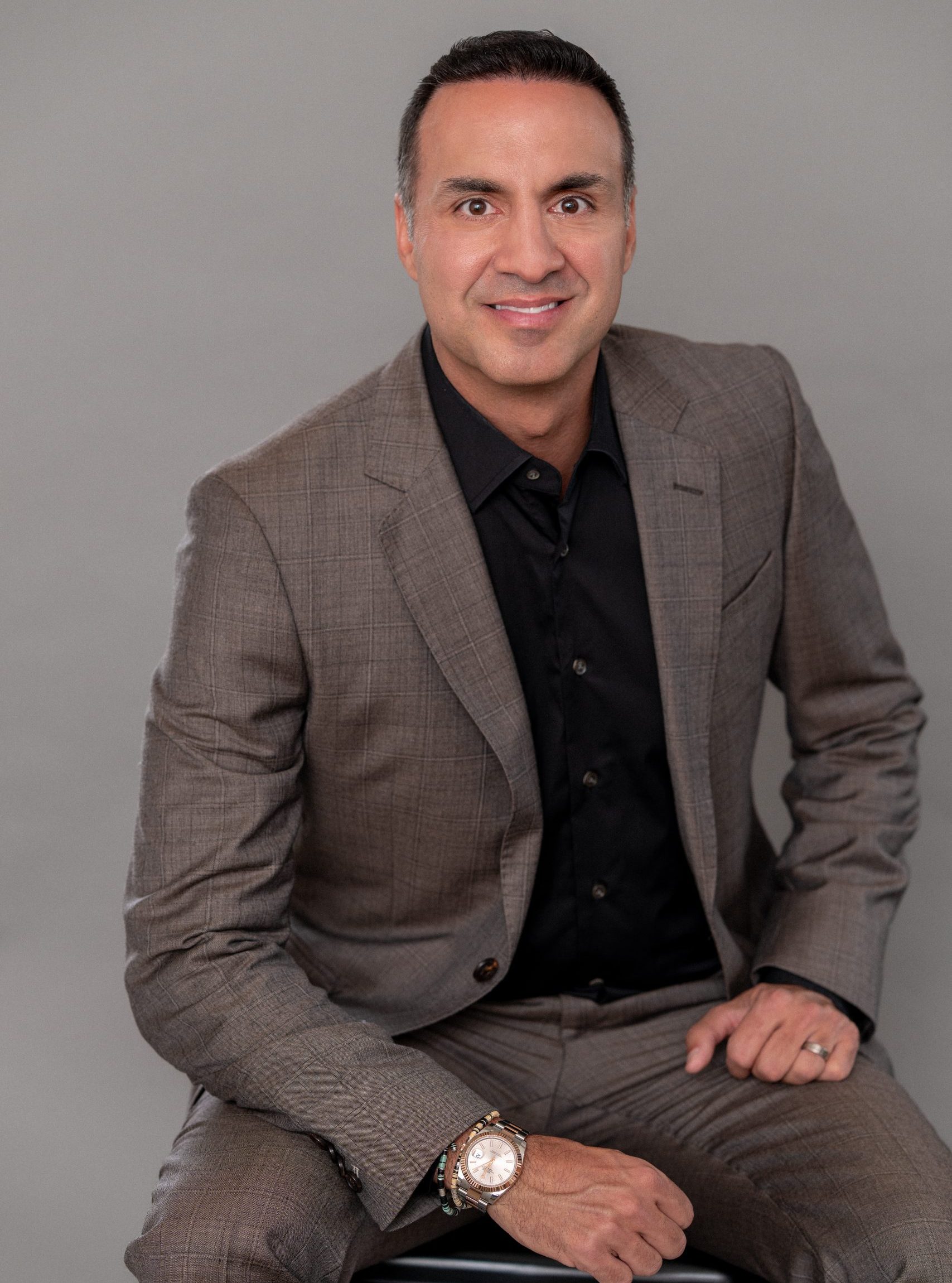 Commercial real estate executive seated in studio portrait wearing brown suit.