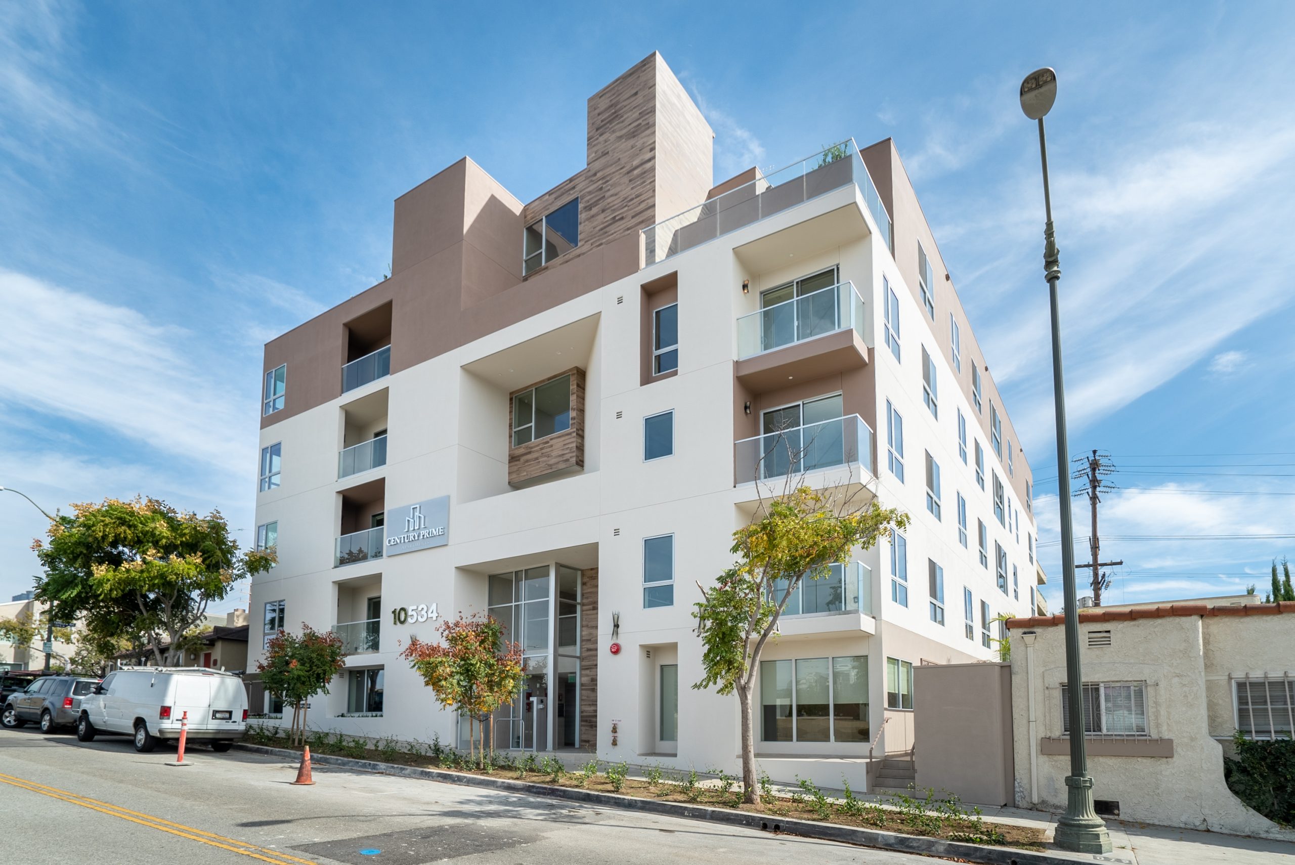 Modern real estate development with white apartment building and street view.