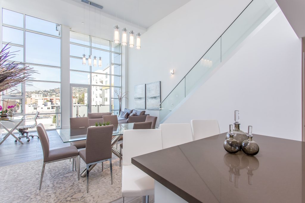 Luxury modern condo interior with open staircase and floor-to-ceiling windows.