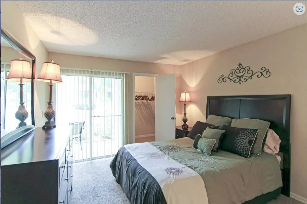 Comfortable apartment bedroom with large windows, soft neutral décor, and contemporary furnishings.