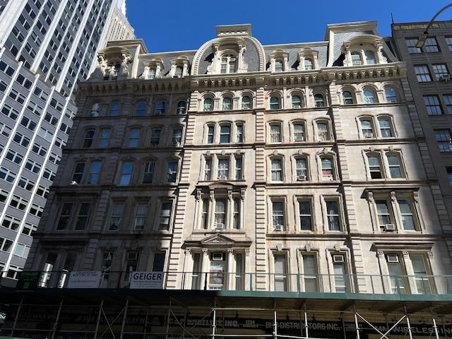 Restored historic building featuring decorative stonework, arched windows, and classic architectural elements in an urban business district.