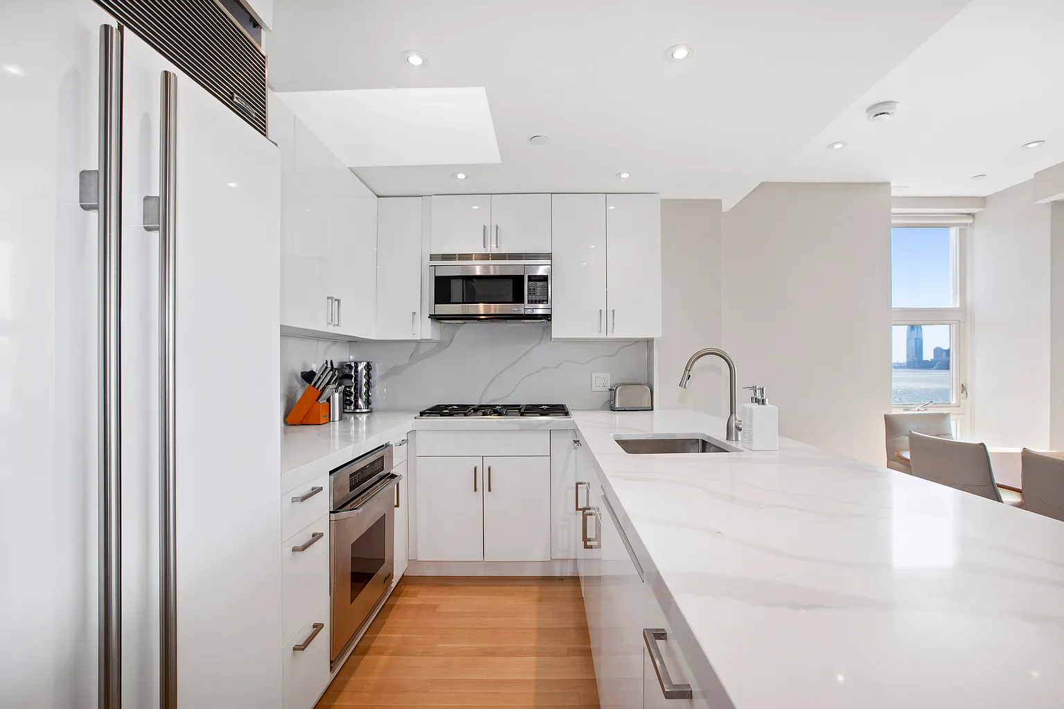 Contemporary kitchen featuring white cabinetry, stone countertops, stainless steel appliances, and a bright open layout.