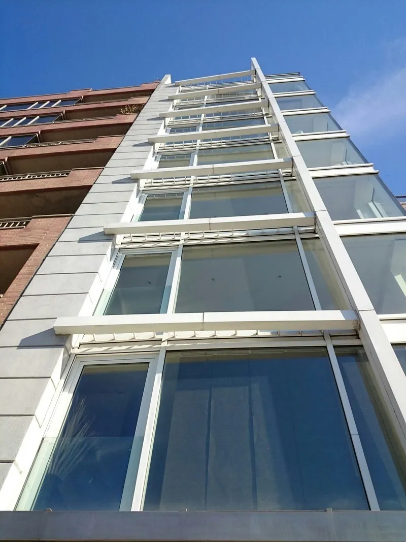 Low-angle view of a contemporary residential building with a glass façade and private balconies.