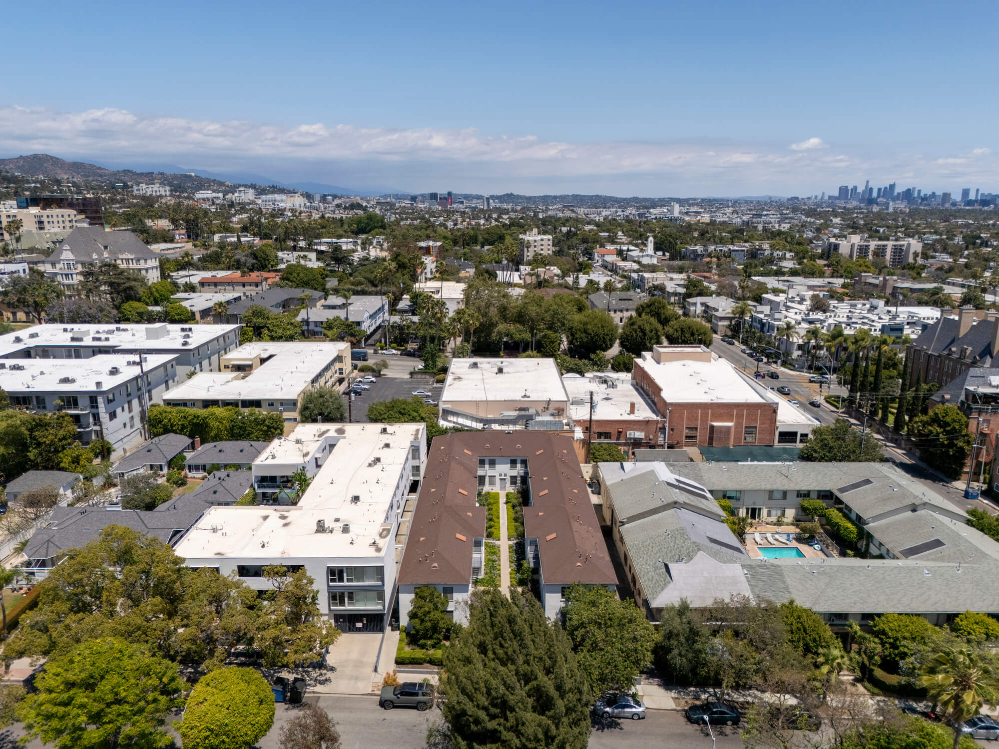 Aerial perspective of a residential apartment community with multiple buildings, internal walkways, and mature landscaping.