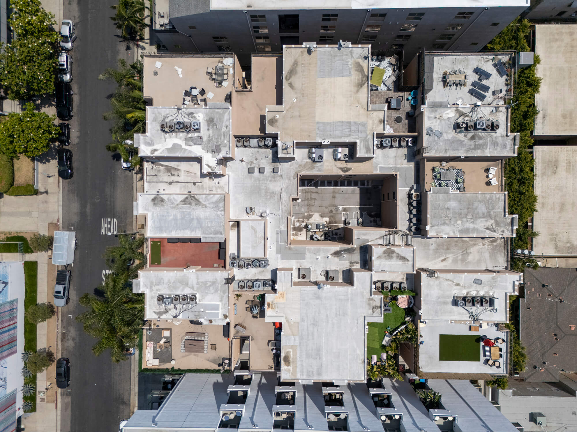 Top-down aerial view of a multifamily property showcasing rooftop features, building layout, and adjacent streets.