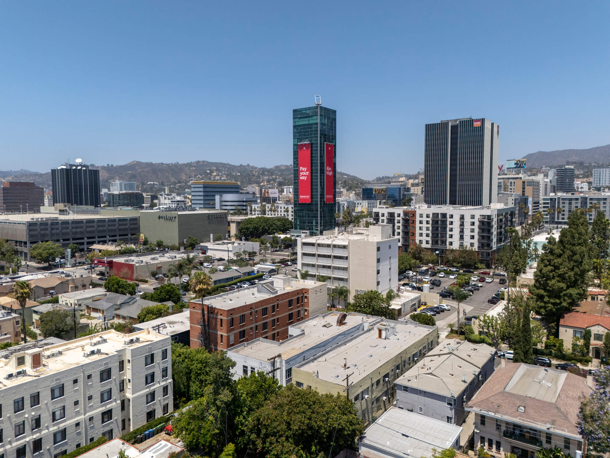 Elevated view of a mixed-use urban district with residential buildings, office towers, and a city skyline in the background.