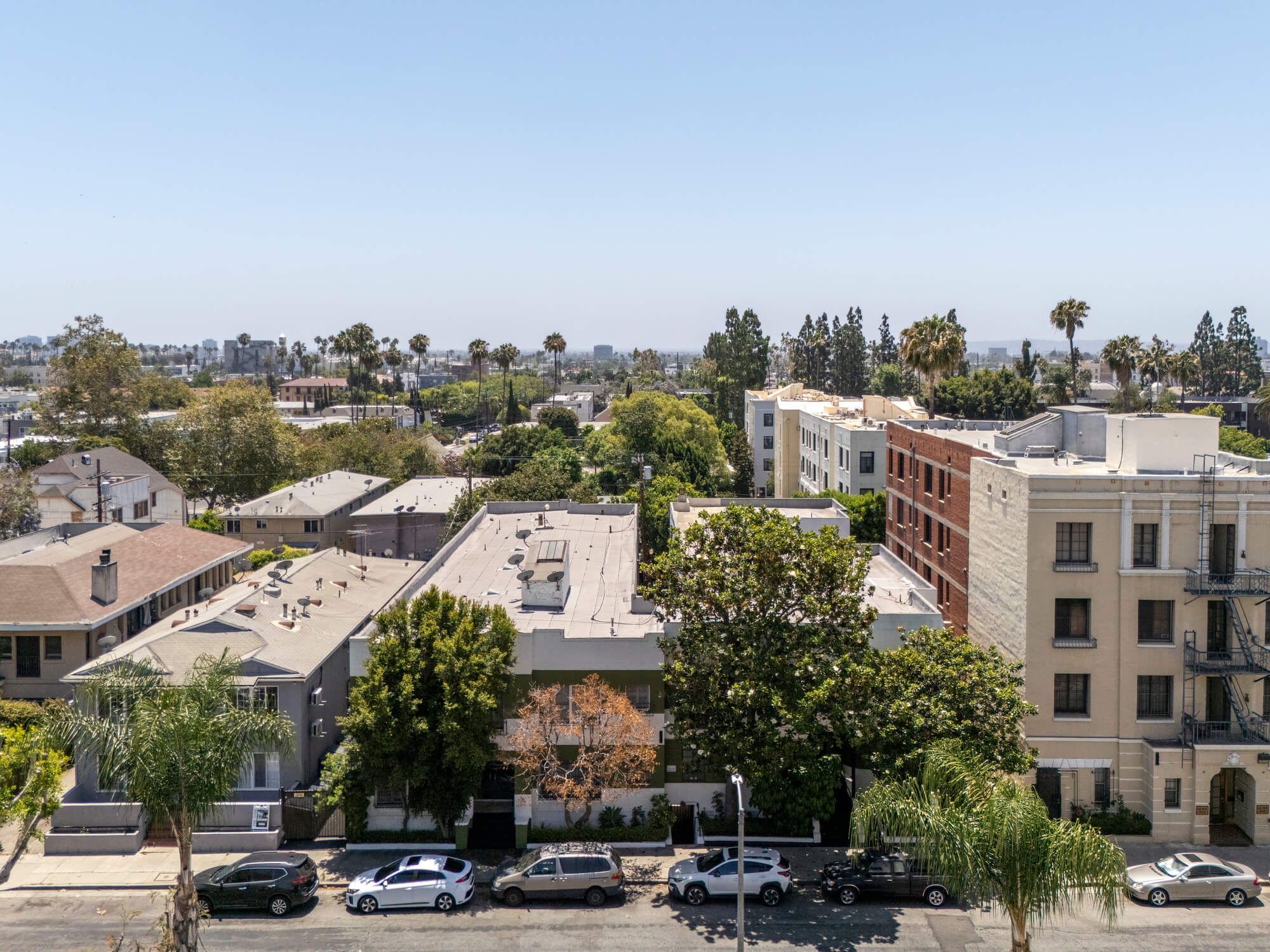 View across a residential neighborhood featuring contemporary apartment buildings, landscaped grounds, and mature trees.