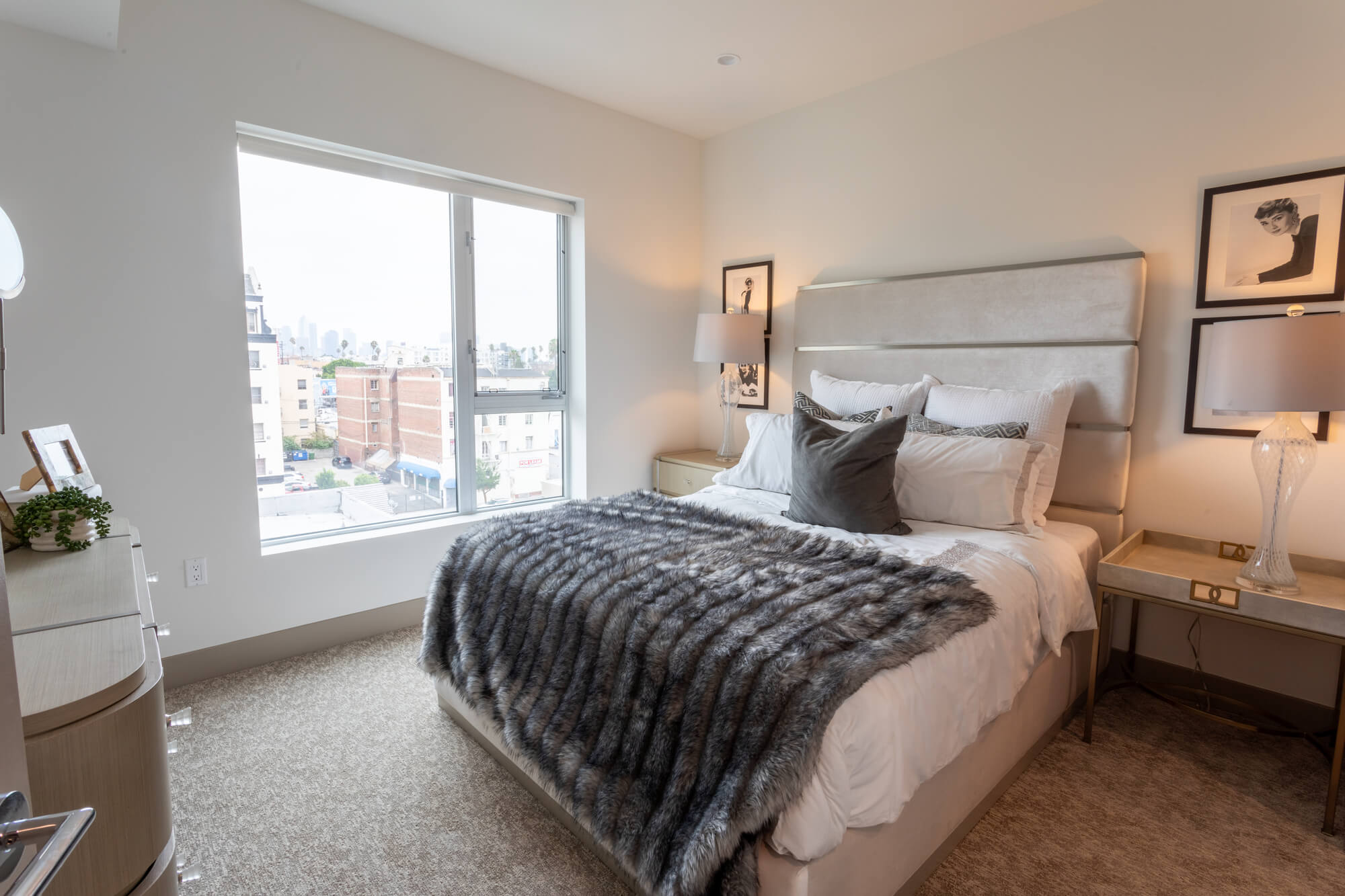 Bright bedroom featuring large windows, neutral décor, upholstered furnishings, and abundant natural light.
