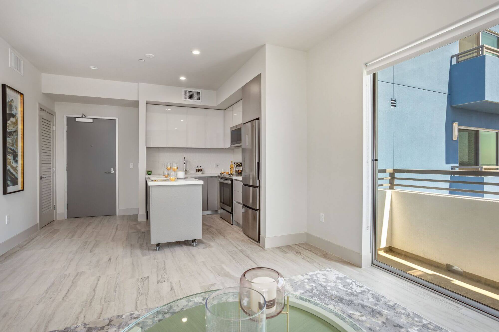 Open-concept apartment interior featuring a modern kitchen, living area, and floor-to-ceiling windows.