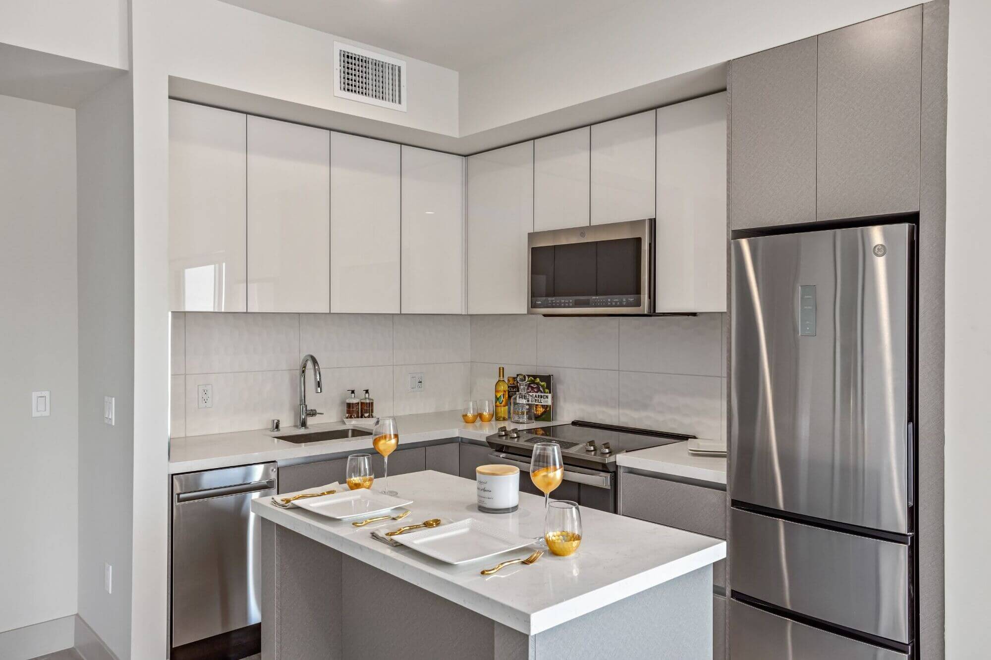 Modern apartment kitchen with stainless steel appliances, stone countertops, and contemporary cabinetry in a multifamily residential property.