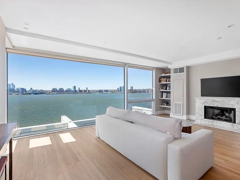 Modern waterfront living room with floor-to-ceiling windows and panoramic ocean views.