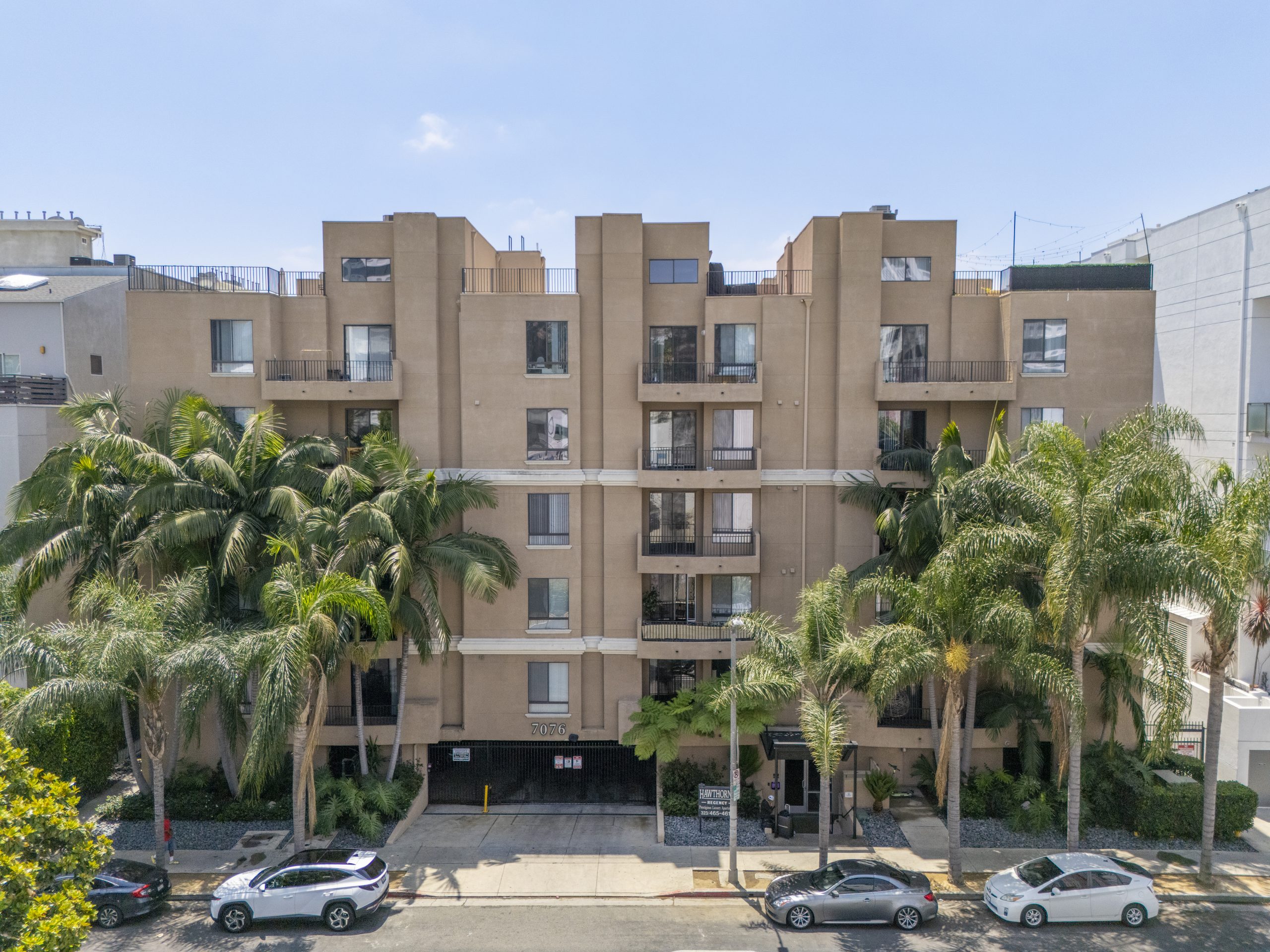 Multi-family residential apartment building with palm trees and landscaped frontage.