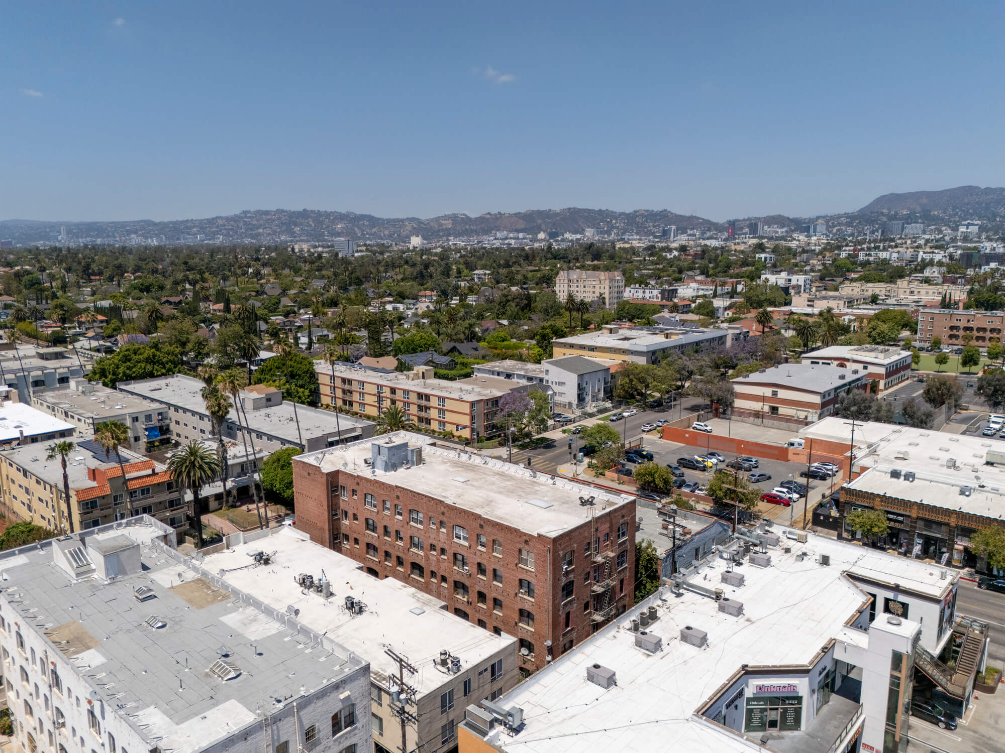 Drone view of a residential neighborhood featuring apartment buildings, commercial corridors, and surrounding city development.