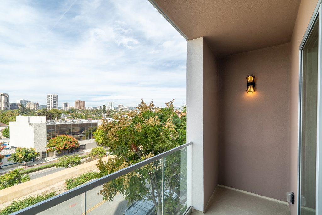 Contemporary apartment balcony with outdoor seating and city skyline views.