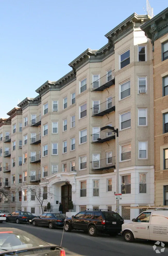 Historic multifamily apartment building exterior on urban residential street.