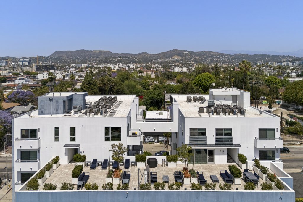 Modern multi-family residential development with rooftop amenities and hillside views.
