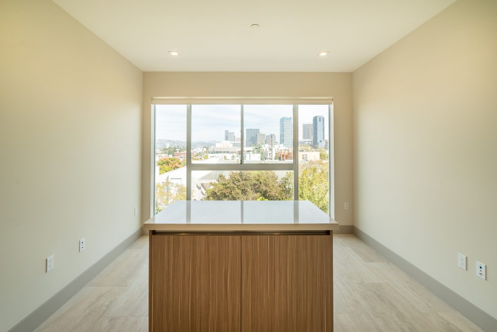 Bright minimalist apartment interior with large window and city skyline view.