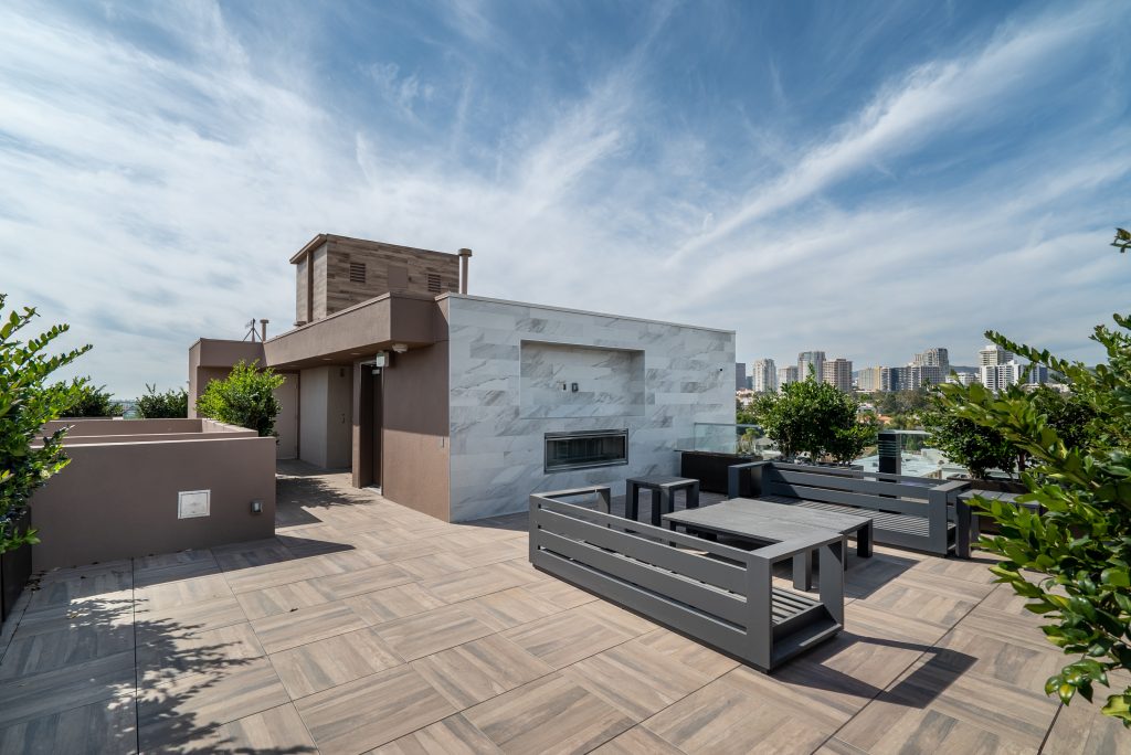 Modern rooftop patio with outdoor lounge furniture and panoramic city views.