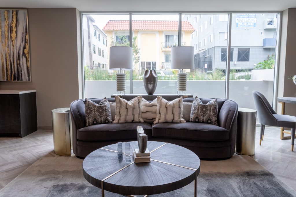Luxury apartment living room with modern furniture and large windows overlooking courtyard.